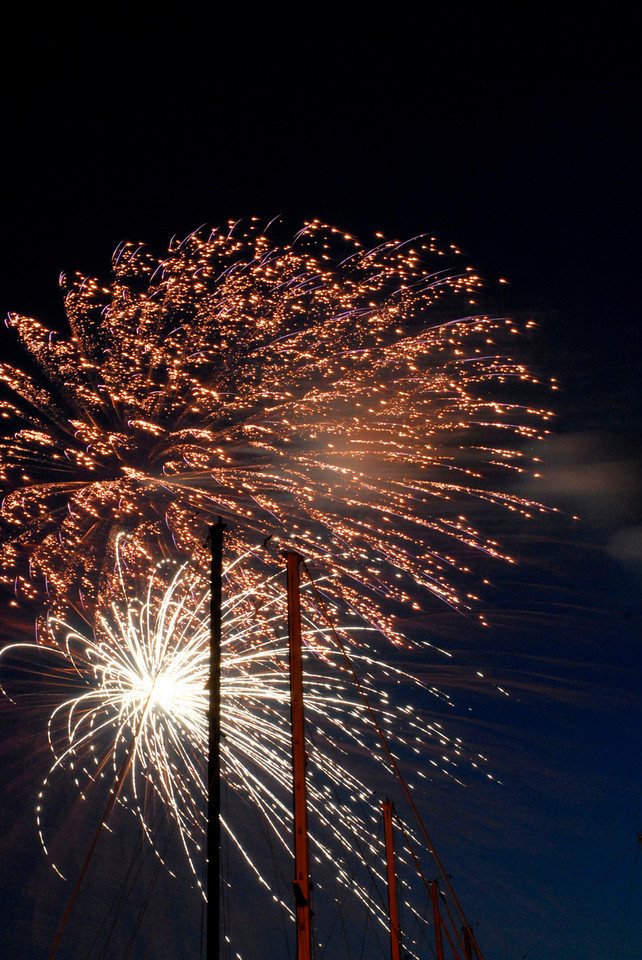 Fourth of July fireworks above sailboat masts at the waterfront